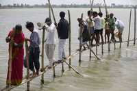 Pobladores cruzan por un puente construido con bambú en la inundada provincia de Darbhanga, en el este de India