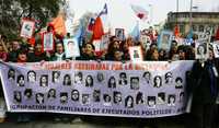 Familiares de víctimas de la dictadura de Augusto Pinochet, portan fotografías de mujeres asesinadas, ayer, durante una marcha en Santiago de Chile