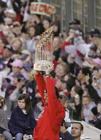 El catcher Jason Varitek, capitán de los Medias Rojas, sostiene el trofeo de la Serie Mundial durante el desfile de la victoria en la calle Tremont de Boston