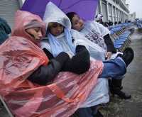 Vanessa Núñez, Elizabeth Paz y Jessica Paz esperan en Boston, bajo la lluvia provocada por remanentes de la tormenta tropical Noel, el comienzo de la ceremonia de presentación del destructor USS Sampson, que cuenta con misiles teledirigidos de la clase Arleigh Burke