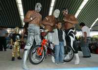 Místico (al centro), Sagrado y Máscara, posan con niños durante la entrega de juguetes en el barrio de Tepito