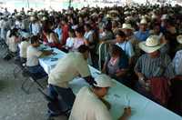 Pobladores del municipio de Landa de Matamoros, en Querétaro, reciben de personal del Programa de Acción Comunitaria, vales de gasolina por cien pesos y otros cupones para canjear apoyos que van de tinacos hasta bultos de cemento