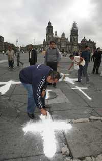 Universitarios pintaron ayer en el Zócalo cruces de cal por los muertos en el operativo en la discoteca News Divine