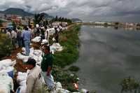 Trabajadores del gobierno capitalino  colocan costales en la presa de regulación El Salado, dado el riesgo de que se desborde por las lluvias