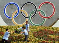 Trabajadores adornan con flores la entrada de uno de los estadios en Pekín