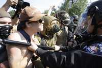 Policías contienen a manifestantes que se congregaron afuera de la sede de la Convención Nacional Demócrata que comienza hoy en Denver