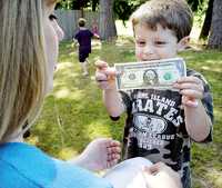 Una mamá observa orgullosa a su hijo que muestra un billete de dólar que ganó vendiendo pelotas de golf recuperadas a practicantes de ese deporte, en Maple Valley, estado de Washington, Estados Unidos, donde la crisis financiera ha desalentado el consumo y las familias pasan más tiempo en casa