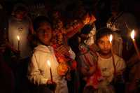 Dos niños llevan una cruz hecha con mazorcas y una muñeca de maíz que representa a la virgen, como parte de la celebración del tlamanes en la comunidad de Chilocuil, en Tamazunchale, San Luis Potosí