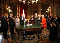 Barack Obama durante la firma de su primer acta como presidente de Estados Unidos, en el Capitolio. Le aplauden, por parte de la Cámara de Representantes, el líder de la minoría, John Boehner; el líder de la mayoría, Steny Hoyer, y la presidenta Nancy Pelosi; el vicepresidente Joe Biden, y la jefa del Comité Conjunto del Congreso para Ceremonias de Toma de Posesión, Diane Feinstein; el senador Bob Bennett; el líder de la mayoría del Senado, Harry Reid, y Lisa Brown, empleada de la Casa Blanca