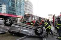 Bomberos auxilian a las dos personas que resultaron lesionadas en el auto que volcó por invadir el carril confinado del Metrobús, en Insurgentes